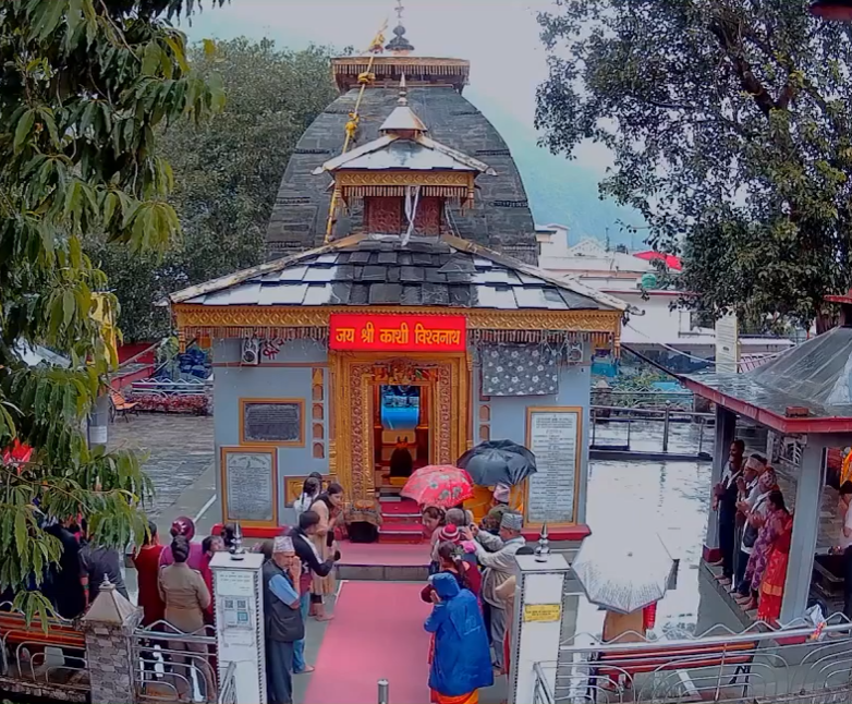 Kashivishwanth Temple in Uttarkashi with a tall spire and detailed carvings. The temple is surrounded by green hills and has a peaceful, scenic backdrop."
